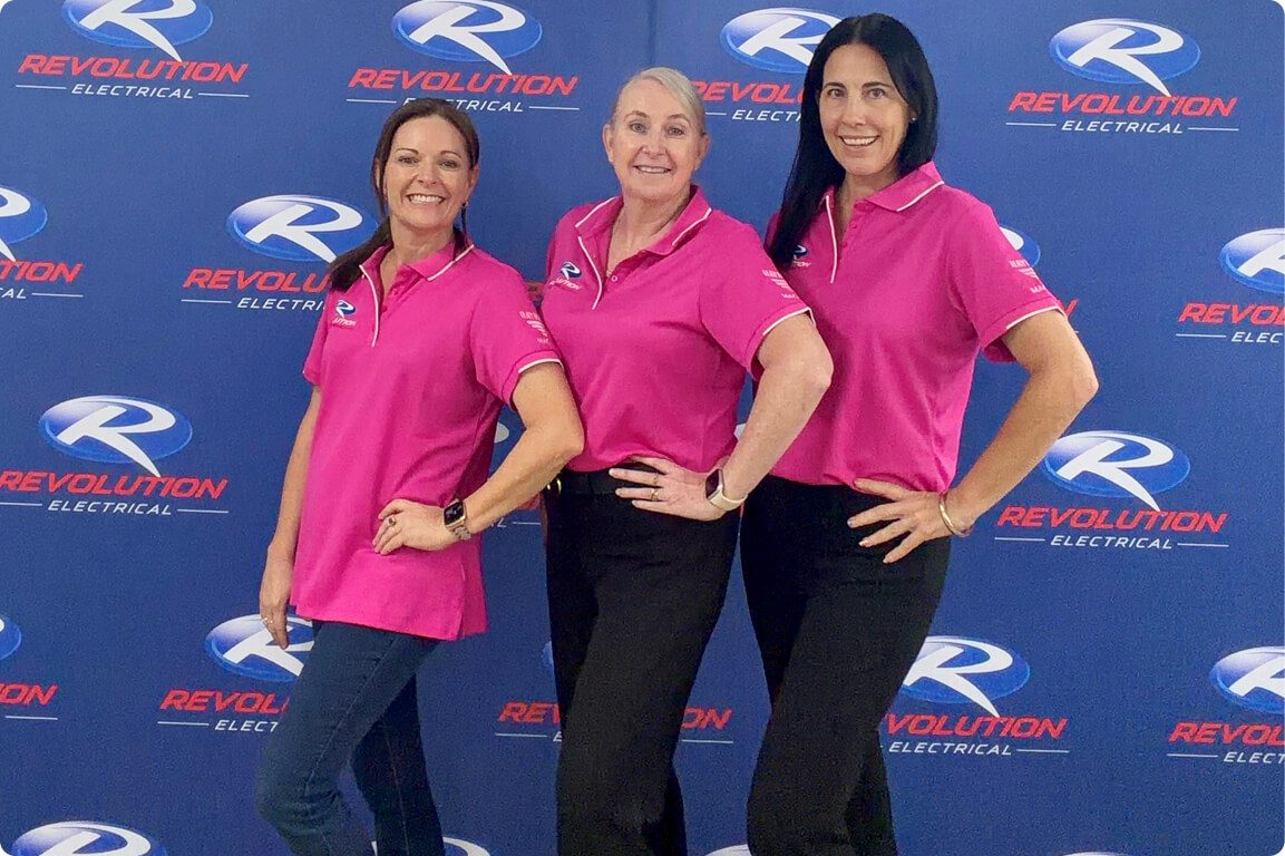 Revolution Electrical administration team standing in front of branded backdrop, representing customer support and business operations.